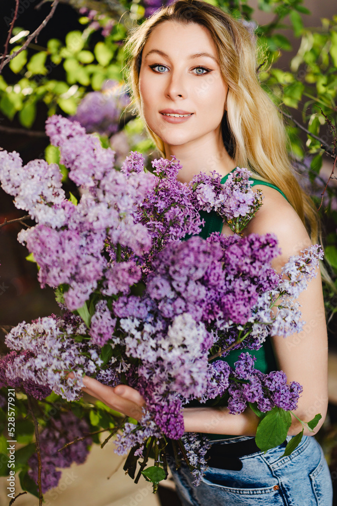a beautiful woman in a green top and jeans with lilac flowers. a beautiful woman in a green top and jeans with lilac flowers.