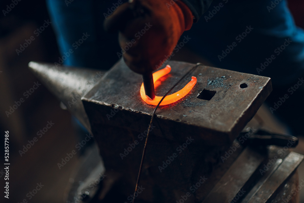 Blacksmith forges and making metal horseshoe with hammer and anvil at forge. Blacksmith forges and making metal horseshoe with hammer and anvil at forge.