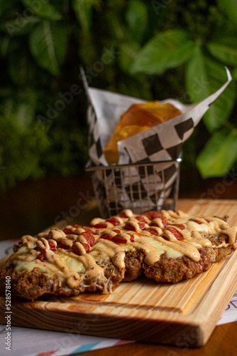 Milanese with topping. Milanesa covered with arugula, tomatoes, cheese. Breaded meat. Italian food. Fried meat. Beef, chicken meat, pork meat.