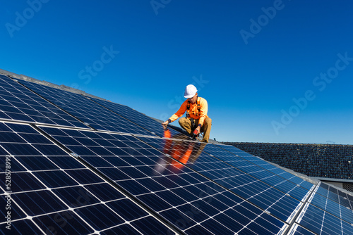 Solar panel technician with drill installing solar panels photo