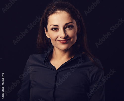 Beautiful thinking toothy laughing business woman with folded arms in blue shirt on black background with empty copy space. Closeup