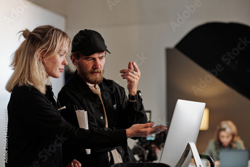Photos Young female assistant of videographer pointing at computer screen during discus