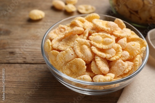 Bowl with tasty corn flakes on wooden table, closeup