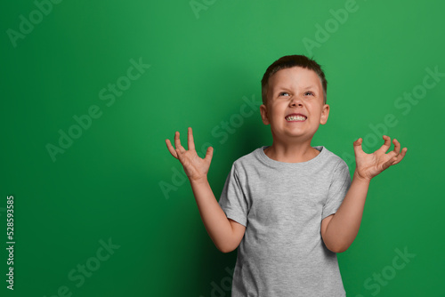 Foto Angry little boy on green background, space for text