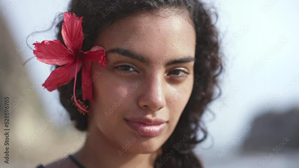 Young island woman with traditional hawaiian flower on tropical beach. Concept of paradise island, exotic vacation getaway, dream travel to Tahiti, French Polynesia.
