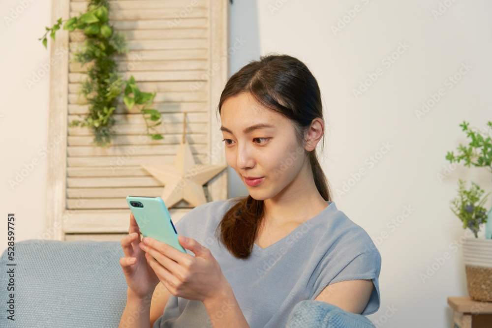 夜のリビングでスマホを見る女性