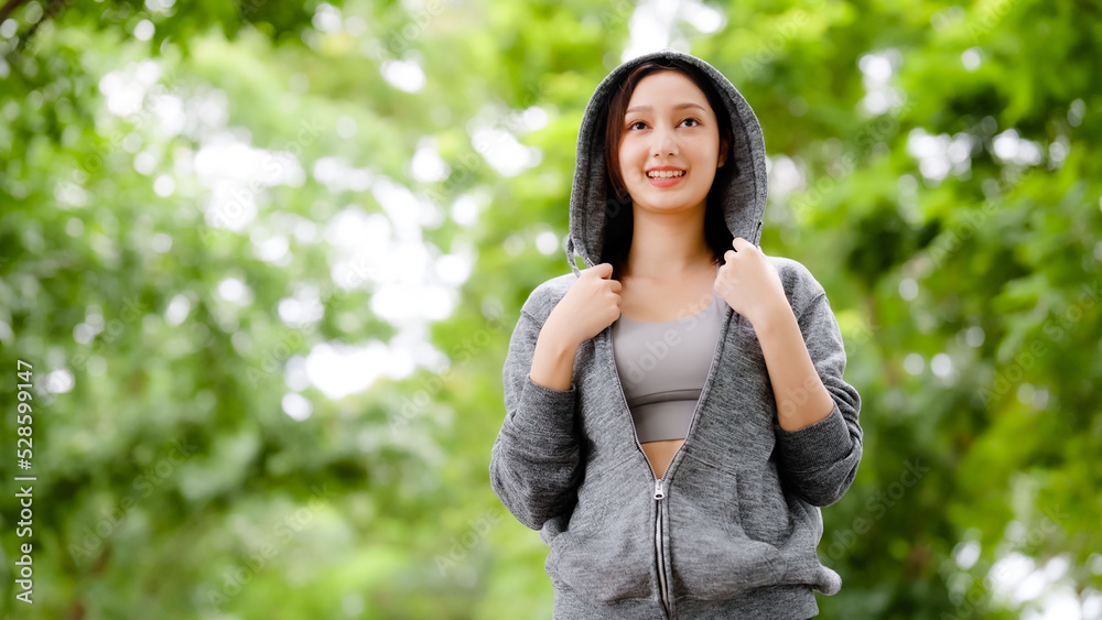 Asian woman wearing jacket is engaged in fitness in public park. Healthy lifestyle concept, sports outdoor activities in park Asian woman wearing jacket is engaged in fitness in public park. Healthy lifestyle concept, sports outdoor activities in park