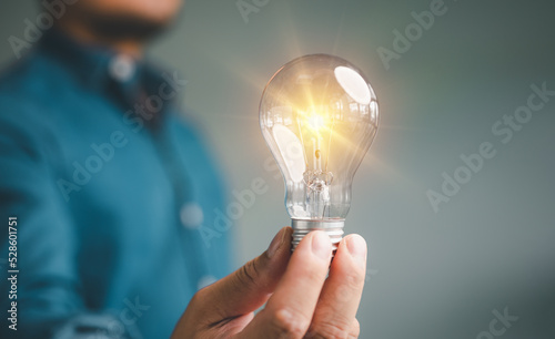 Idea innovation and inspiration concept. Hand of man holding illuminated light bulb, concept creativity with bulbs that shine glitter. Inspiration of ideas for sustainable business development...
