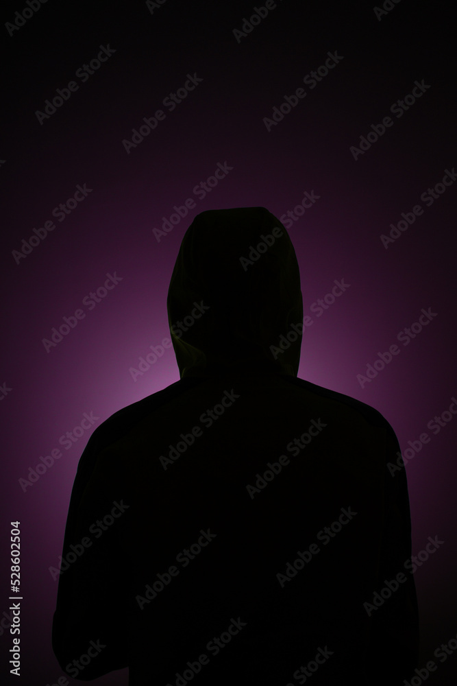 Anonymous alone in the dark back photo wearing hoodie purple light background