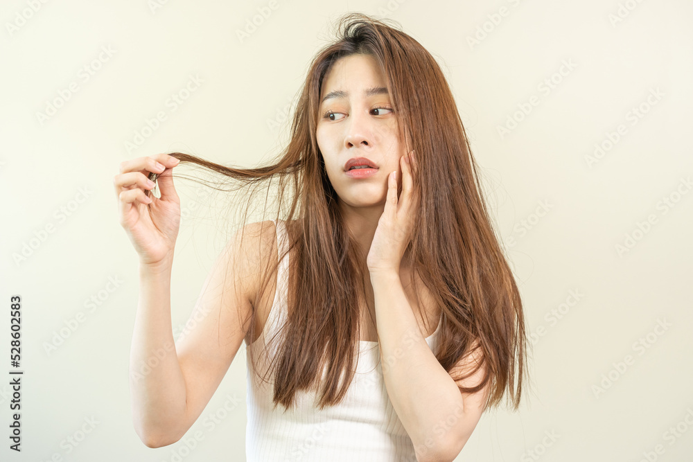 Damaged Hair, frustrated asian young woman, girl hand in holding splitting ends, messy unbrushed dry hair with face shock, long disheveled hair, health care of beauty. Portrait isolated on background. Damaged Hair, frustrated asian young woman, girl hand in holding splitting ends, messy unbrushed dry hair with face shock, long disheveled hair, health care of beauty. Portrait isolated on background.