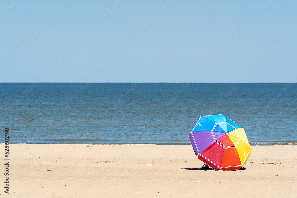 Sunny beach with rainbow umbrella