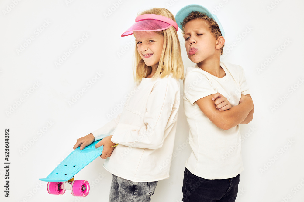 Modern teenagers posing together in caps with skateboard light background Modern teenagers posing together in caps with skateboard light background