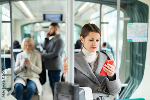 Positive woman reading from mobile phone screen in tram