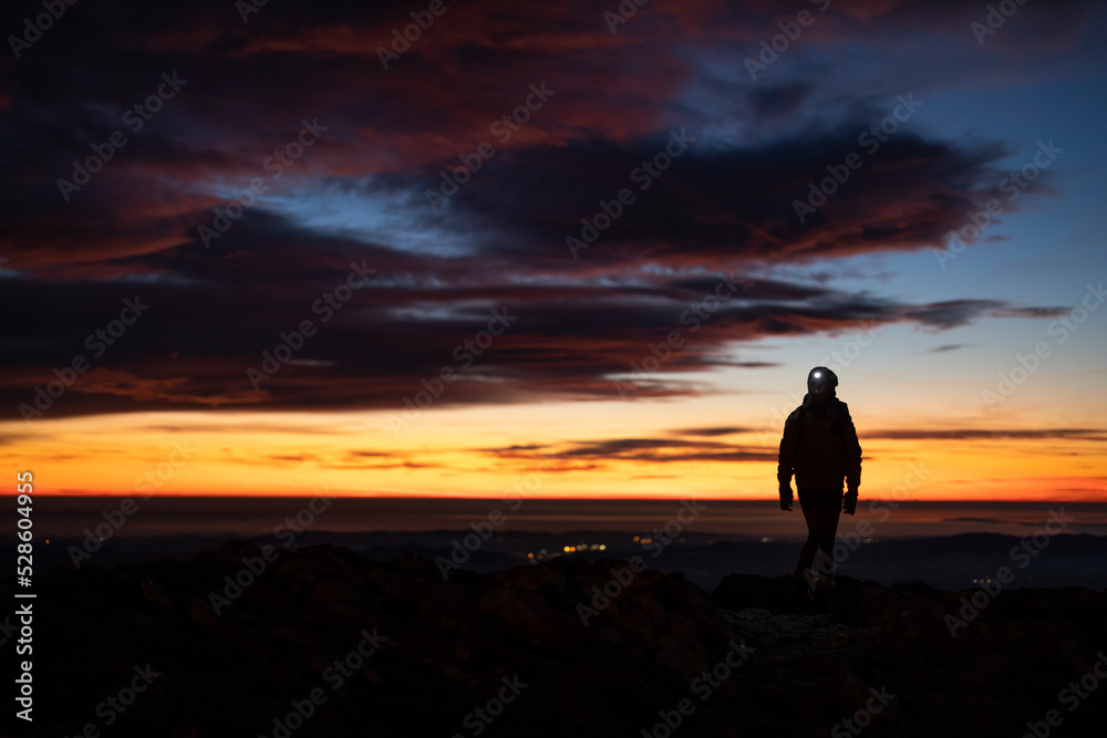 Hiker hiking Uphill in Evening Night Wilderness landscape with a help of a Headlight