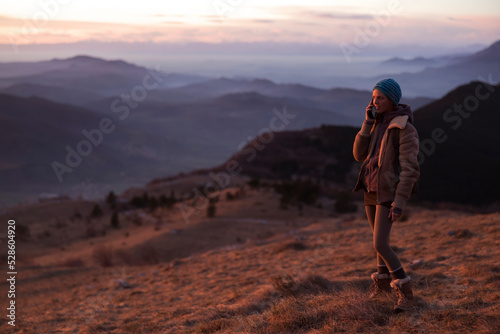 Mid Adult Woman Talking on a Mobile Phone From A Remote location High Above a Valley