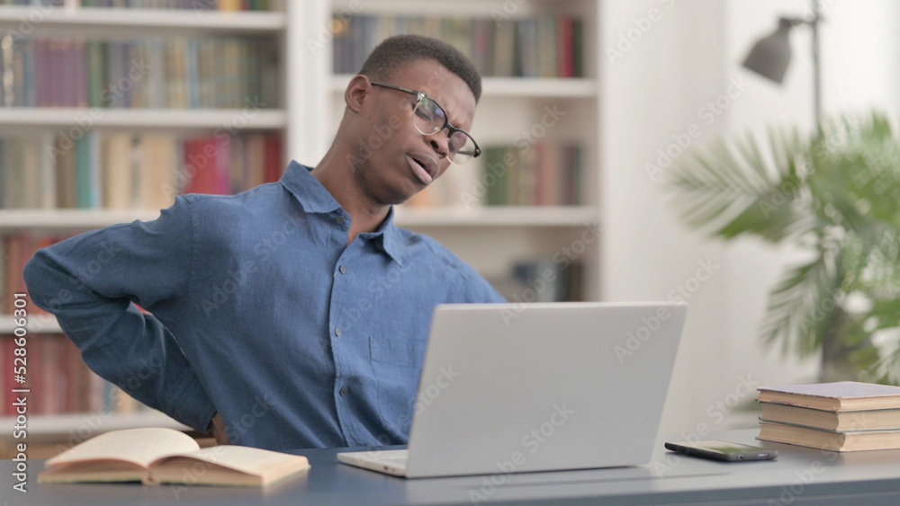 Young African Man having Back Pain while using Laptop in Office