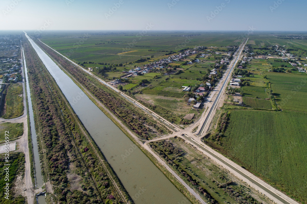 Artificial irrigation of the soil. Irrigation canal supplies water to irrigated land masses. Aerial View