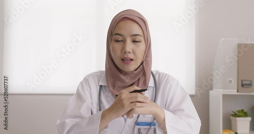 Islam arab GP video call look at camera talk share on telemedicine telehealth teleconsult clinic platform app at office. Young medic health care worker work for asia people tele consult online visit. photo