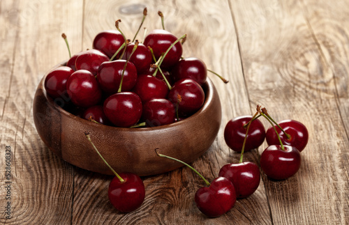 red ripe cherries in a wooden bowl on a building board