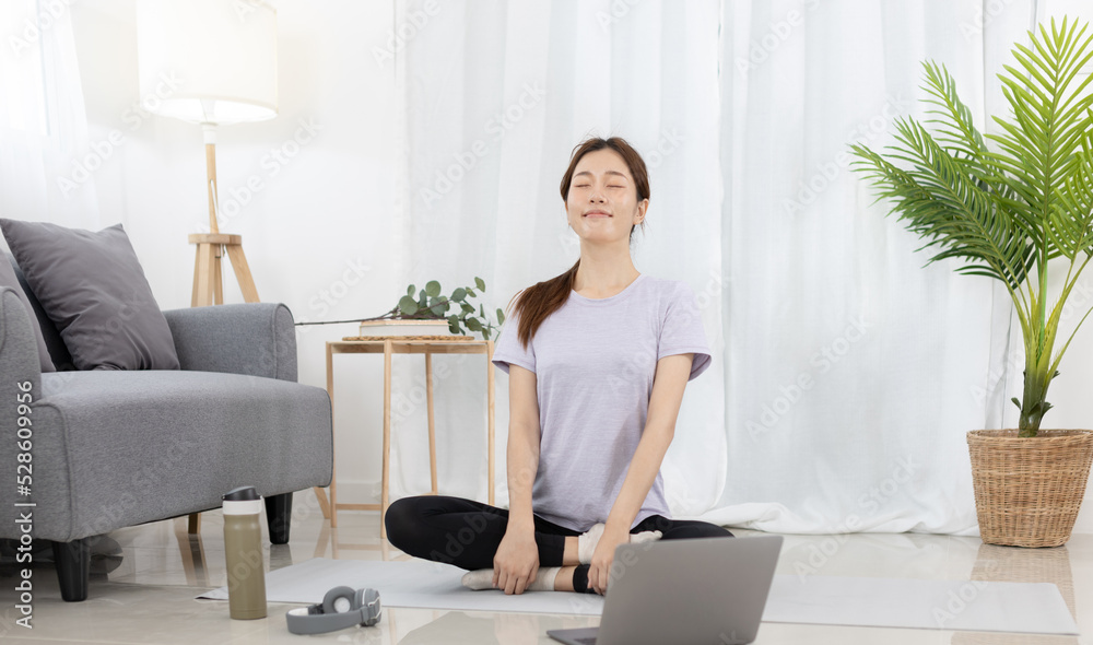 Beautiful Asian woman in sportswear is warming up or doing light exercises in the house with dumbbells and a protein shake or bottle of water and using a laptop at home, Healthy exercise. Beautiful Asian woman in sportswear is warming up or doing light exercises in the house with dumbbells and a protein shake or bottle of water and using a laptop at home, Healthy exercise.