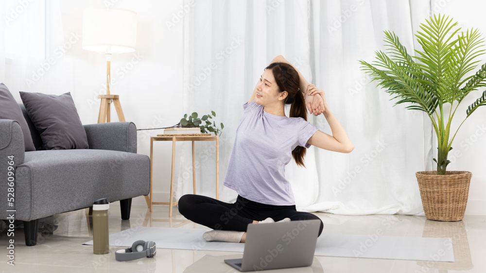 Beautiful Asian woman in sportswear is warming up or doing light exercises in the house with dumbbells and a protein shake or bottle of water and using a laptop at home, Healthy exercise. Beautiful Asian woman in sportswear is warming up or doing light exercises in the house with dumbbells and a protein shake or bottle of water and using a laptop at home, Healthy exercise.
