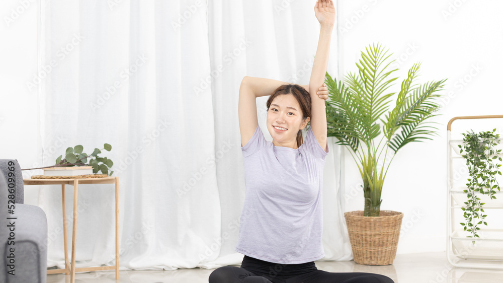 Beautiful Asian woman in sportswear is warming up or doing light exercises in the house with dumbbells and a protein shake or bottle of water and using a laptop at home, Healthy exercise. Beautiful Asian woman in sportswear is warming up or doing light exercises in the house with dumbbells and a protein shake or bottle of water and using a laptop at home, Healthy exercise.