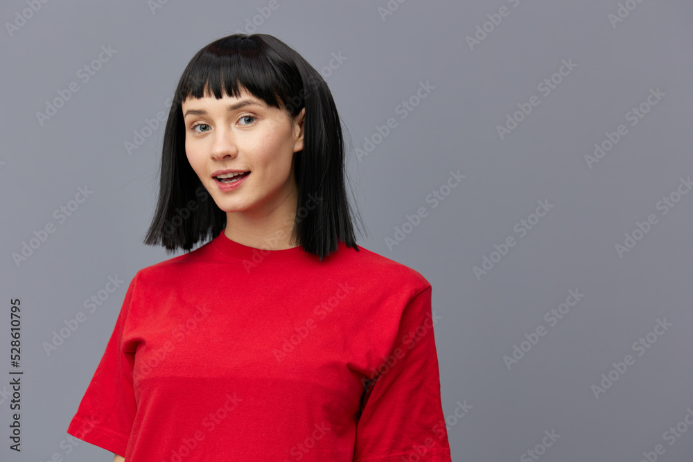 horizontal photo of a beautiful woman with short black hair looking pleasantly into the camera standing on a gray background in a red T-shirt horizontal photo of a beautiful woman with short black hair looking pleasantly into the camera standing on a gray background in a red T-shirt