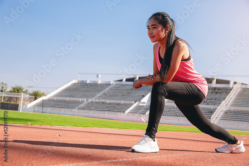 Young woman runner warming up at the racetrack. Fit runner workout, stretch her muscle and warming up at racetrack.