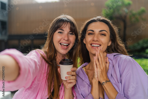 Close up self portrait of two happy women enjoing shopping, drinking coffee. Wearing colrful casual outfit.