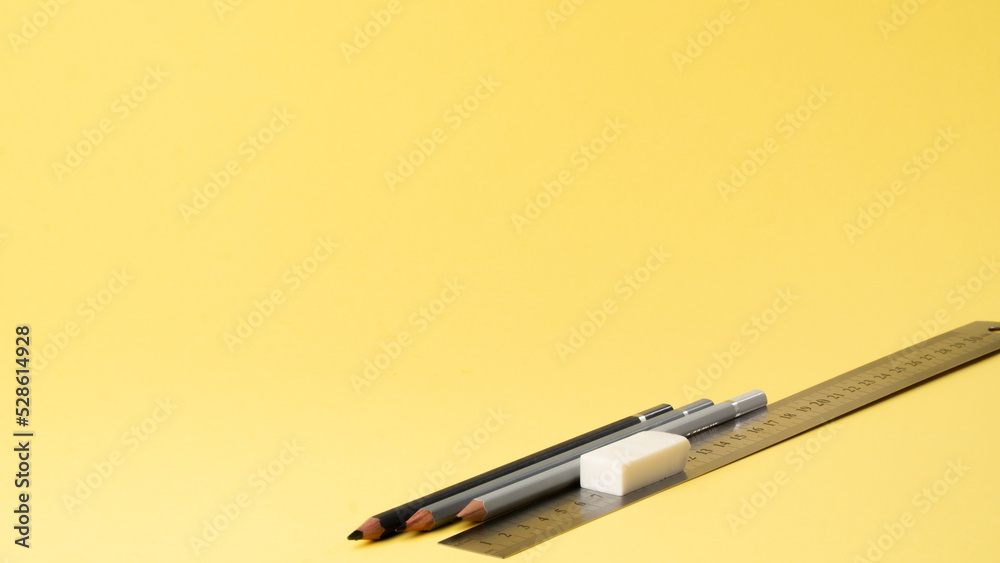 Simple pencils, ruler and eraser on a yellow background Stock Photo