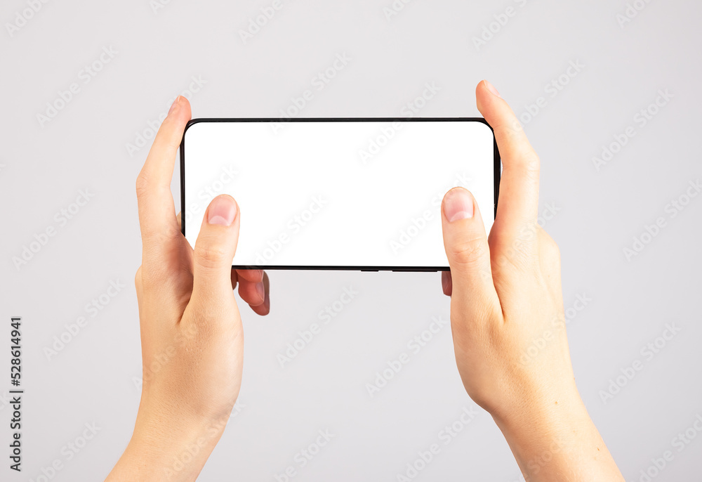 Hands holding phone mockup in horizontal position. Woman using smartphone for playing games. Mobile gaming. template with blank display