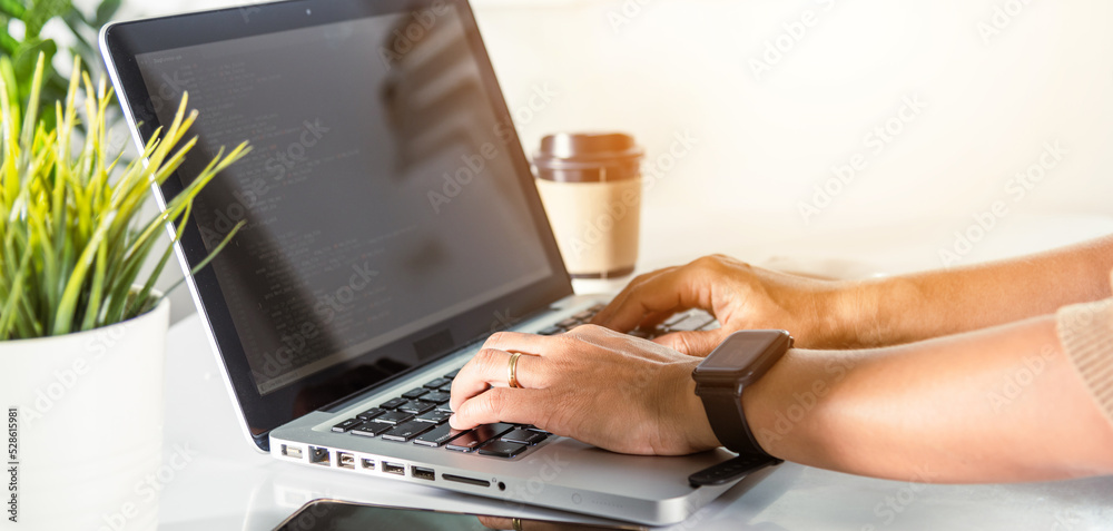 Naklejka premium Web application development. programmer woman writing program code sitting at workplace in office, software developer hands coding HTML programming with laptop computer, IT start up concept, back view