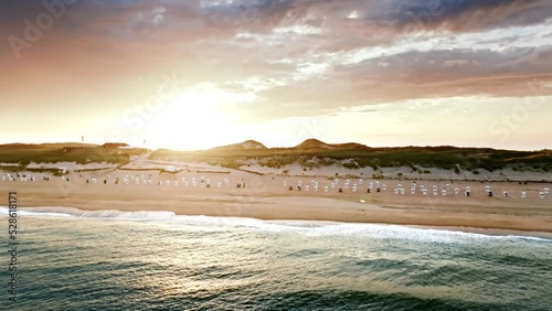 cinematic drone shot from island of Sylt in Germany. Drone flies from sea towards coast and sun photo