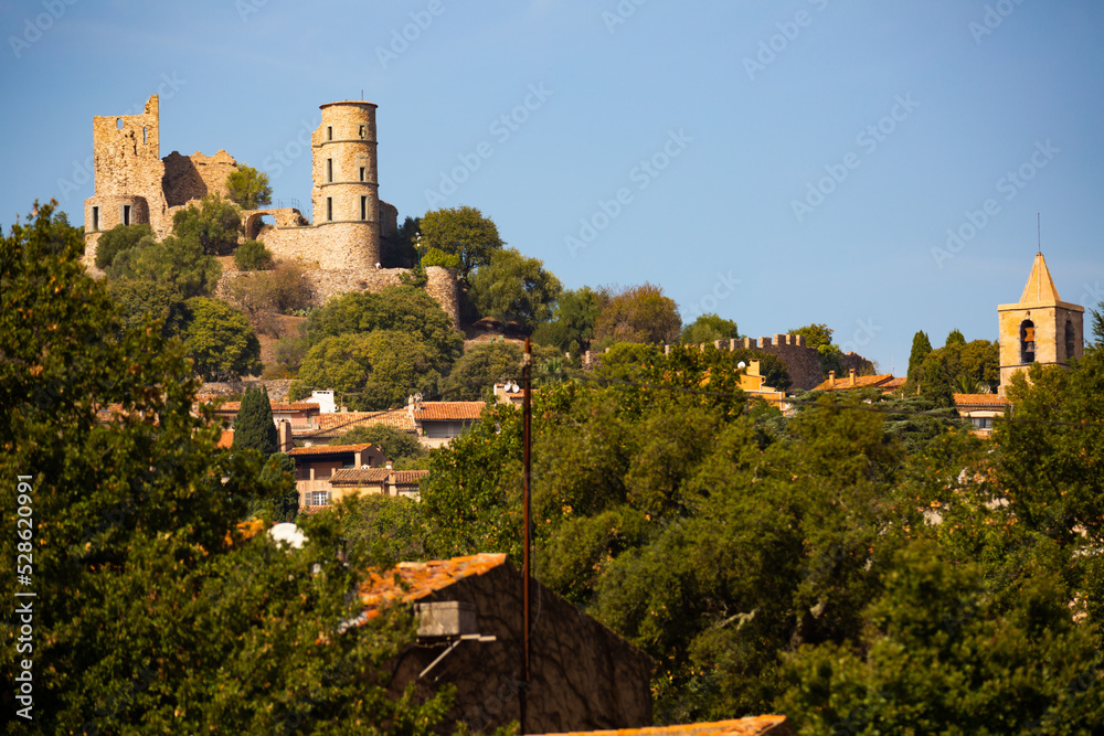 Scenic view of ruins of ancient fortified castle of Grimaud on hill dominating residential houses of village on sunny autumn day, Var department, France