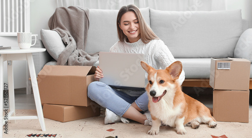 Young woman with laptop, parcels and cute dog at home. Online shopping concept