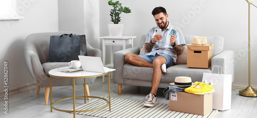Handsome man with credit card, mobile phone and parcels at home. Online shopping concept © Pixel-Shot