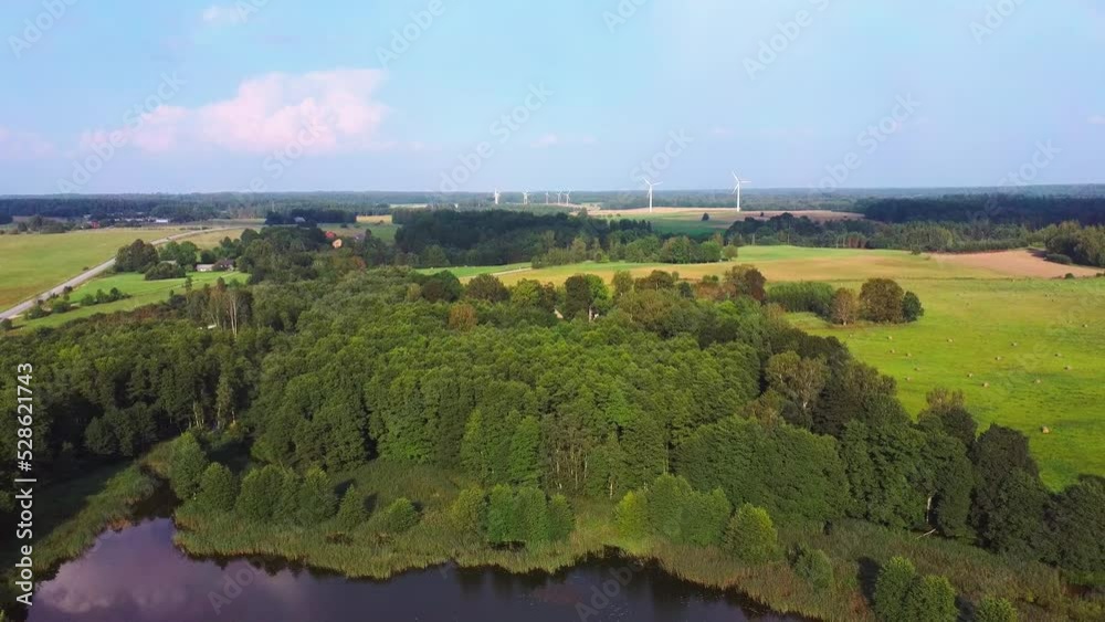Panorama of Alsunga City Lake with Large Wind Turbines for Electric Power Production in Latvia. Alternative Energy, Green Energy Concept, Clean Energy Future Silhouettes Windmills. Camera Moves Back Panorama of Alsunga City Lake with Large Wind Turbines for Electric Power Production in Latvia. Alternative Energy, Green Energy Concept, Clean Energy Future Silhouettes Windmills. Camera Moves Back
