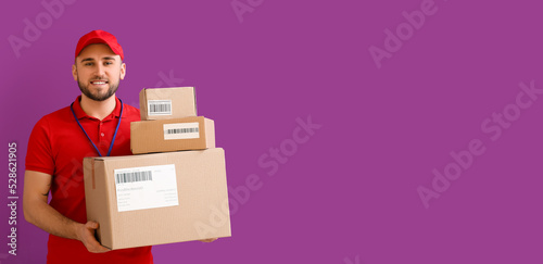 Handsome delivery man with parcels on violet background with space for text
