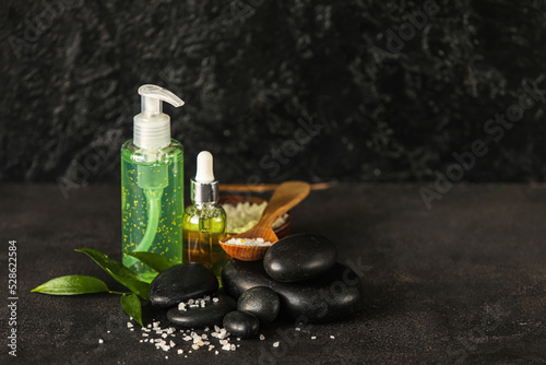 Composition with bottles of cosmetic products  sea salt and spa stones on dark background