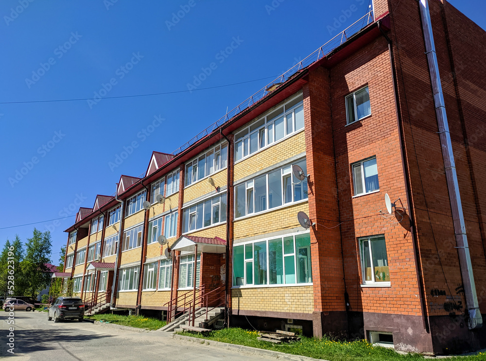 Noyabrsk, Russia - May 31, 2022: View of a three-story brick house with long loggias against the blue sky on a sunny day Noyabrsk, Russia - May 31, 2022: View of a three-story brick house with long loggias against the blue sky on a sunny day