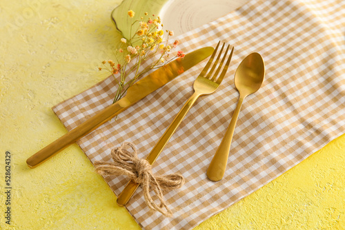 Table setting with flower decor on yellow background