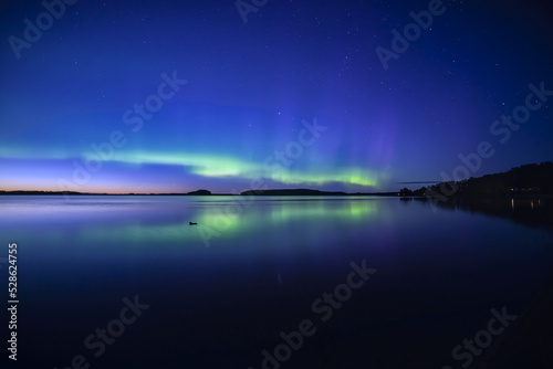 Northern lights dancing over calm lake in north of Sweden