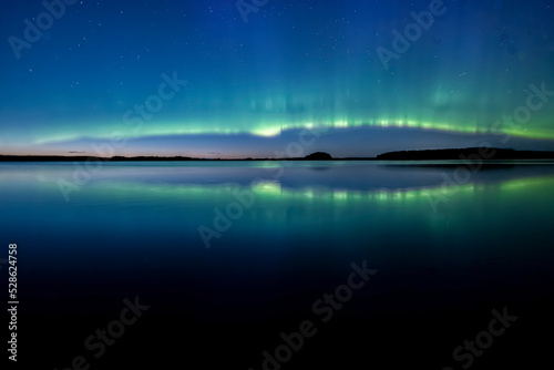 Northern lights dancing over calm lake in north of Sweden