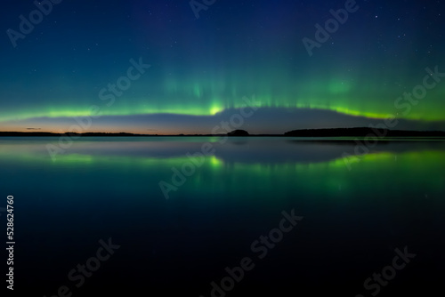 Northern lights dancing over calm lake in north of Sweden