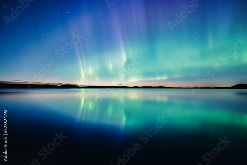 Northern lights dancing over calm lake in north of Sweden