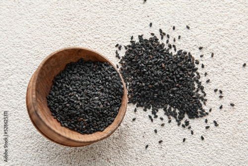 Bowl of black sesame seeds on light background