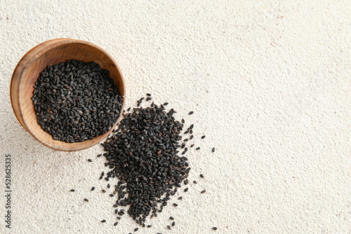 Bowl of black sesame seeds on light background
