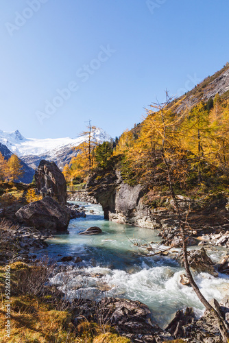 Mountain ravine with autumn colors and a glacier stream photo