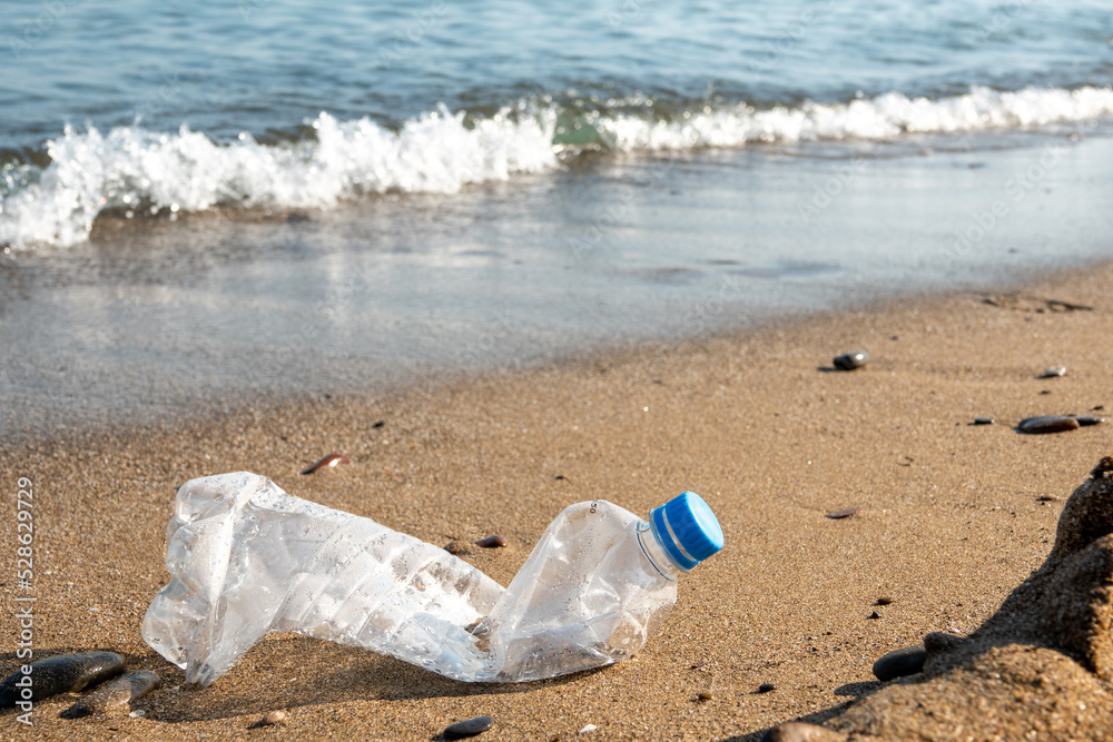 Spilled garbage on the beach of the big city. Empty used dirty plastic bottles. Dirty sea sandy shore the Black Sea. Environmental pollution. Ecological problem. Bokeh moving waves in the background Spilled garbage on the beach of the big city. Empty used dirty plastic bottles. Dirty sea sandy shore the Black Sea. Environmental pollution. Ecological problem. Bokeh moving waves in the background