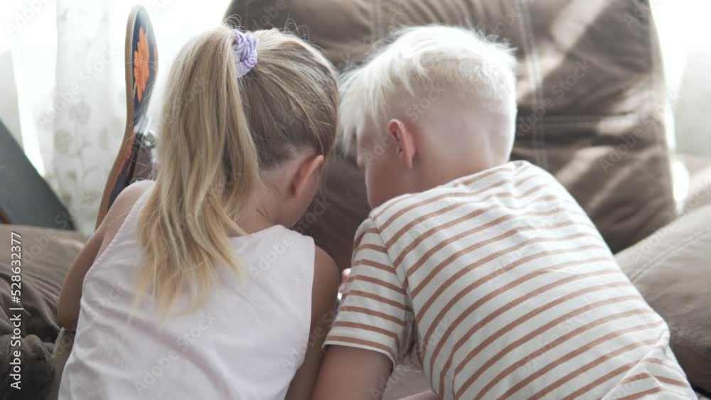 View from the back. Children play with a mobile phone at home. View from the back. Children play with a mobile phone at home.
